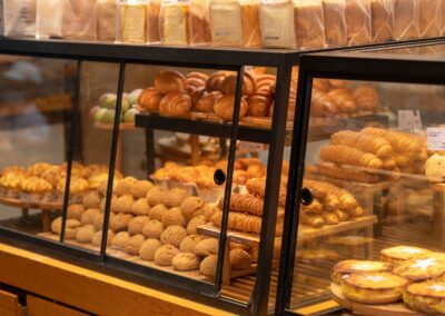A display case filled with assorted pastries and breads in a bakery setting, showcasing fresh baked goods.